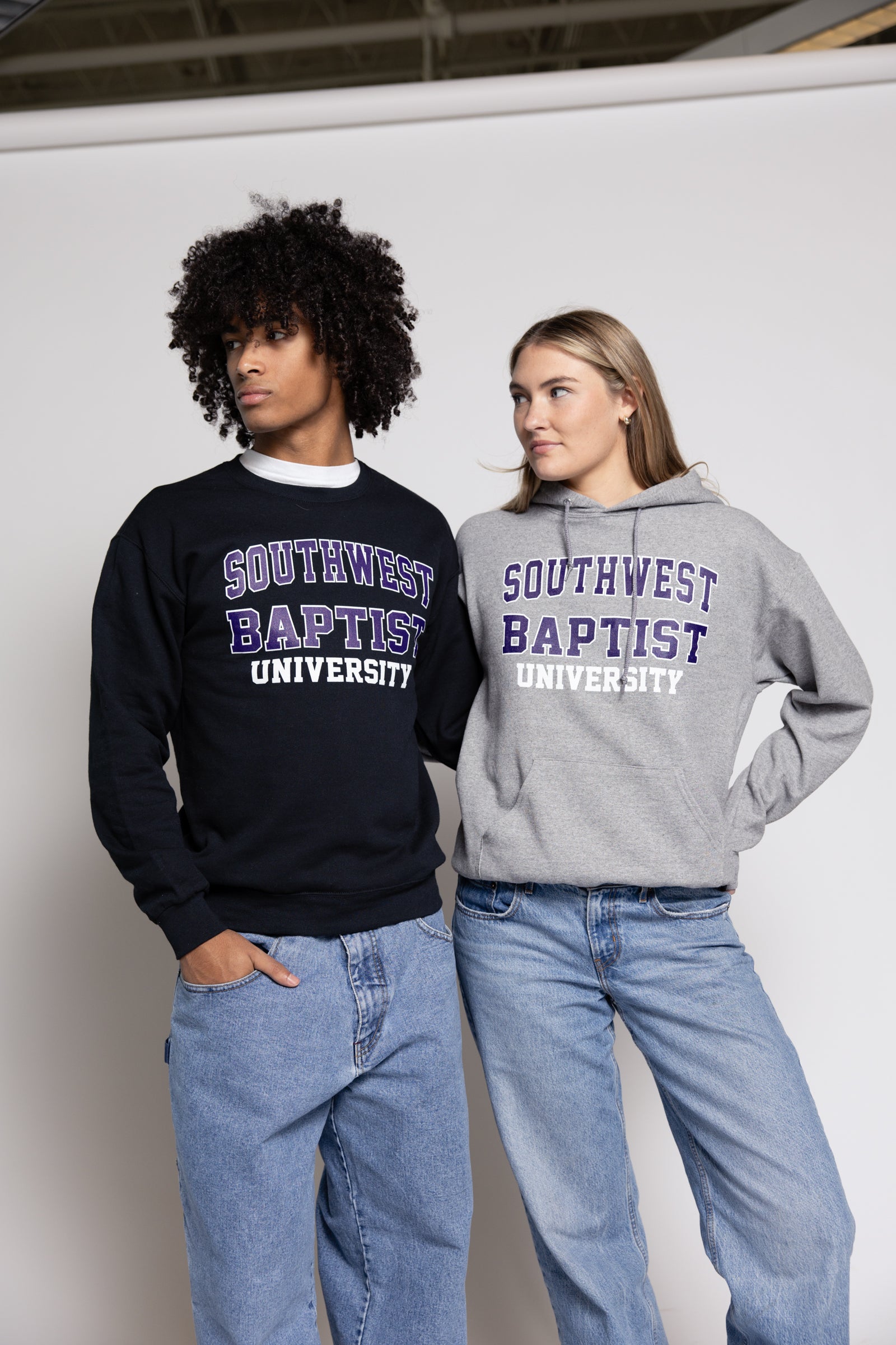 Two people wearing Southwest Baptist University hoodies against a white background