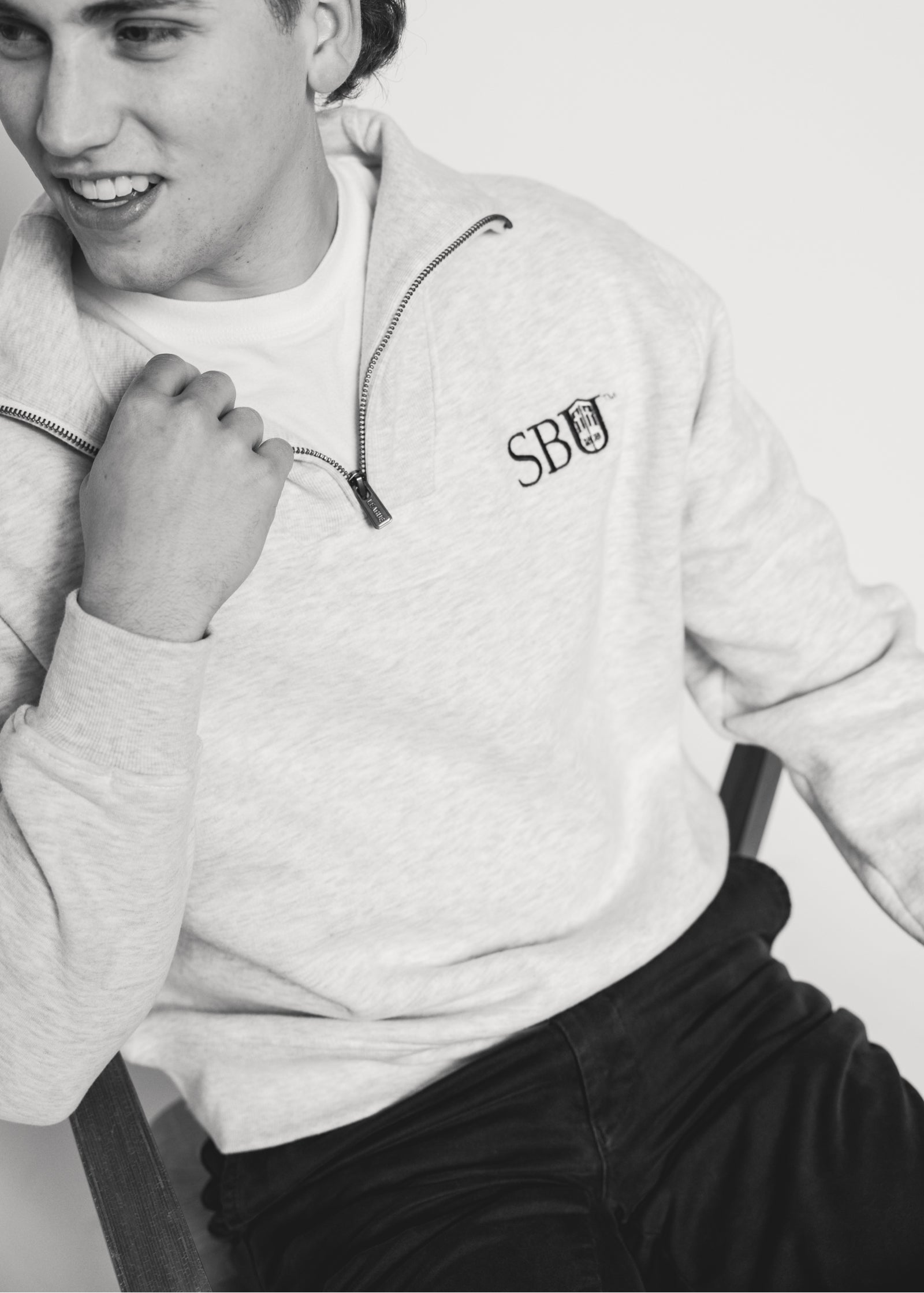 Male wearing a light gray sweatshirt with 'SBU' logo.