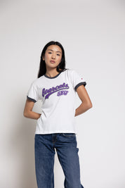 Woman wearing a white t-shirt with purple text and blue jeans on a plain background